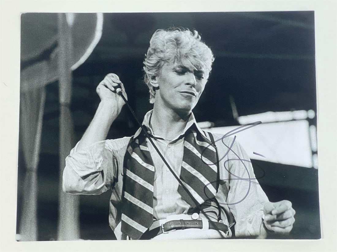 David Bowie Signed/ Autographed Photograph: Striking black and white photograph of the legendary David Bowie performing on stage, signed by the iconic musician. The signature is boldly placed on the lower right corner. A must-have collectible f