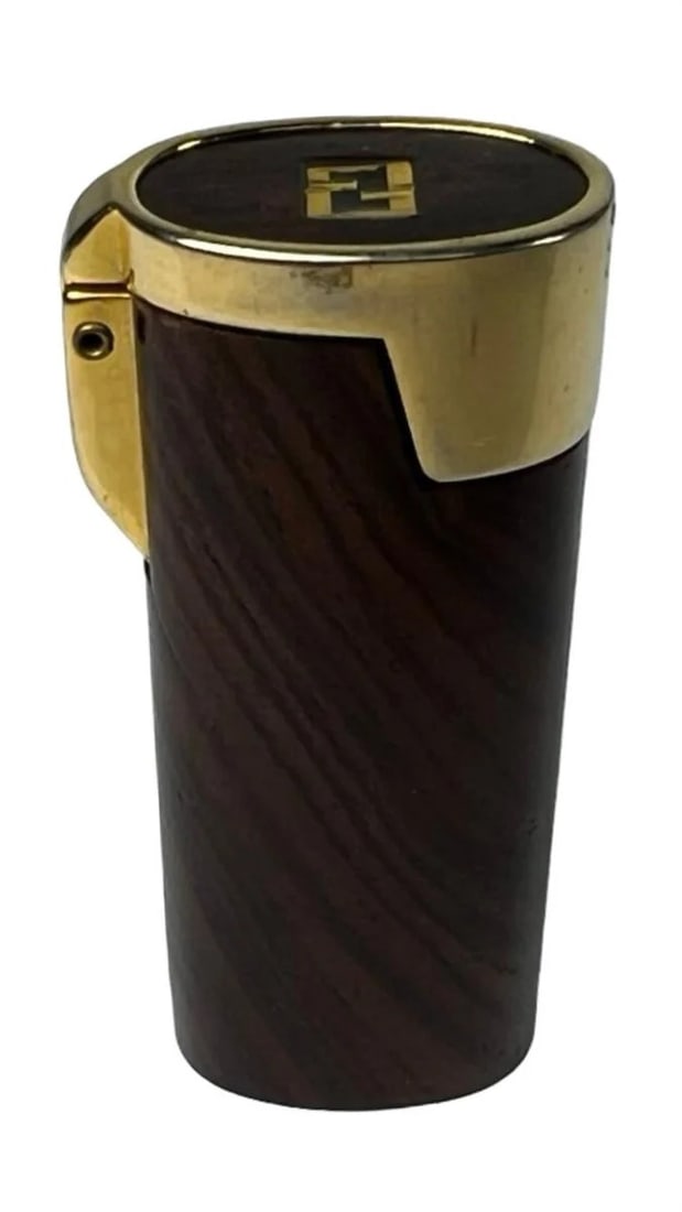 Fendi Designer Cigarette Lighter Cover: Elegant vintage lighter cover crafted in dark wood with polished gold-tone accents and iconic double-F logo. Marked "Made in Italy" on the base. Flip-top design with fitted interior sleeve. A stylish