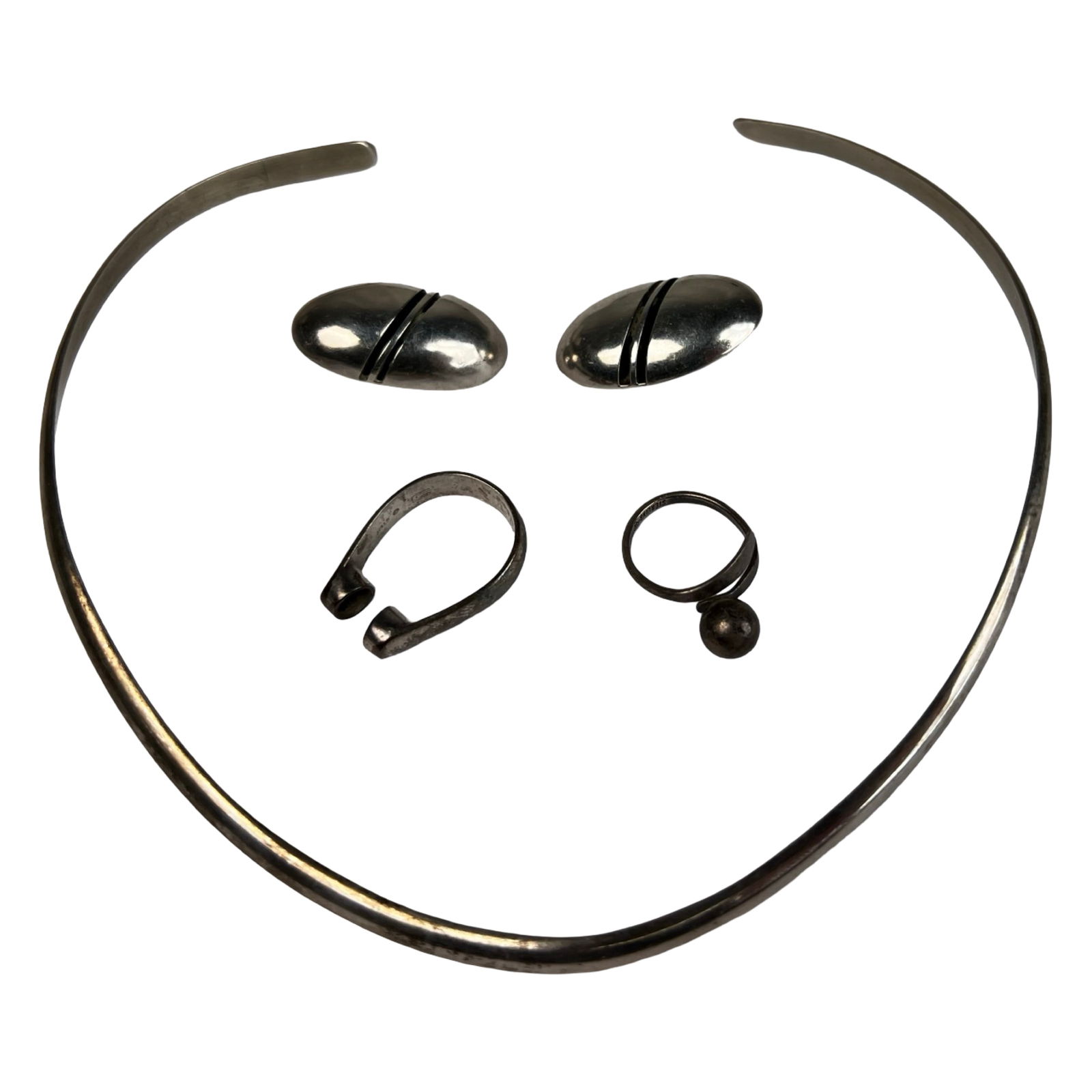 Sterling Silver Modernist Jewelry Set: Group of sterling silver jewelry featuring a sleek open collar necklace, a pair of oval clip-on earrings, and two rings. The necklace measures approximately 5" x 5.5" across and has a clean, minimalis