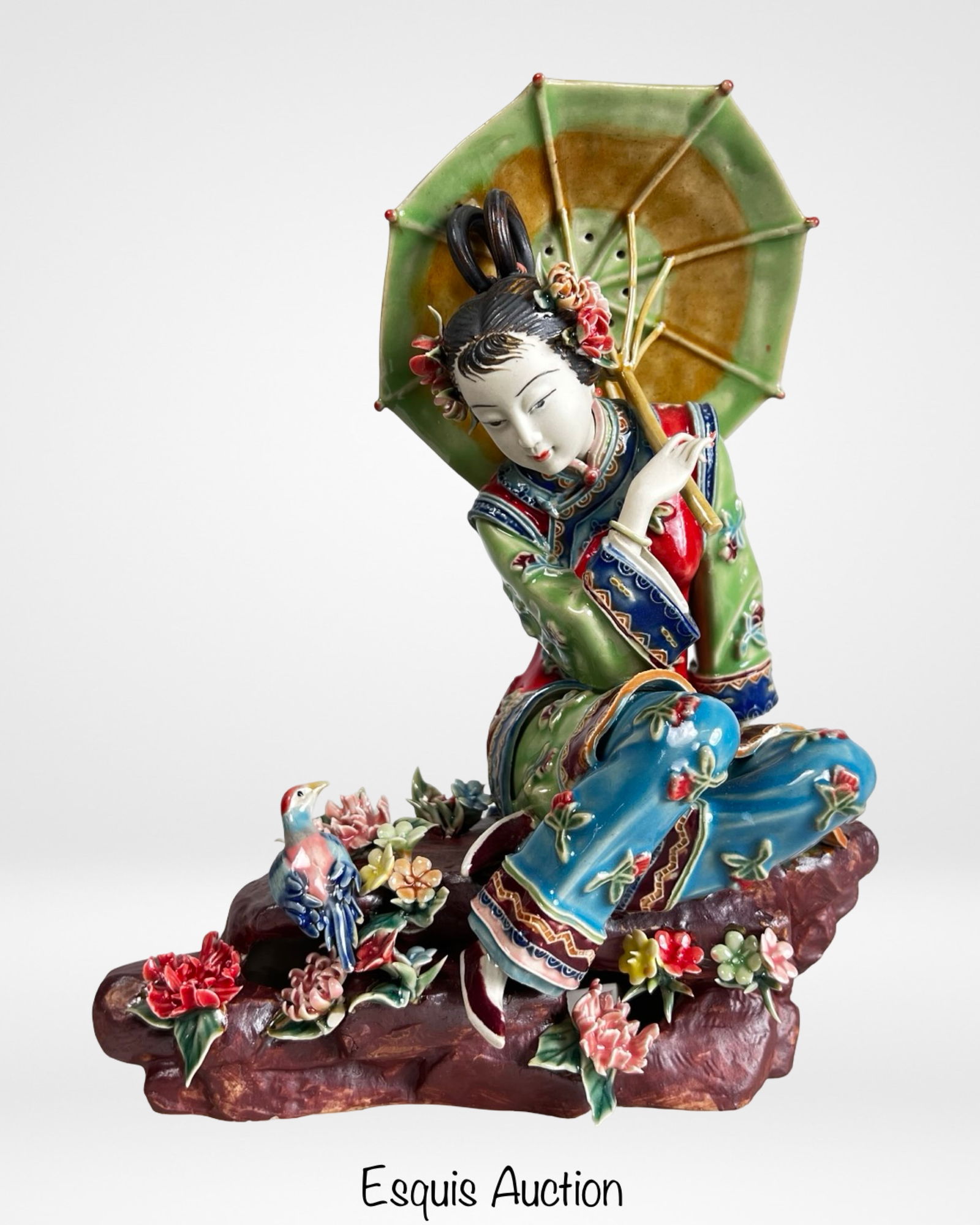 Chinese Wucai Porcelain Figurine of Oriental Lady: Chinese Wucai porcelain figural sculpture depicting an elegant seated lady holding a parasol, dressed in richly enameled robes with vibrant red, green, blue, and gilt accents. The figure is finely det