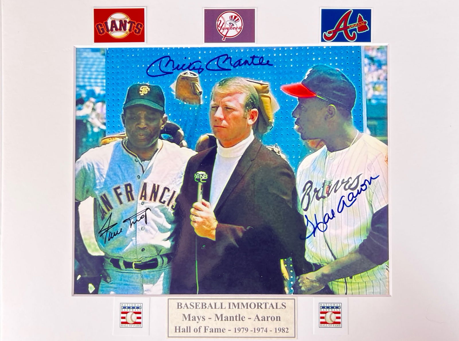 Baseball Immortals Signed Photo- Mantle Mays Aaron: Signed by three legendary Hall of Famers-Willie Mays (1979), Mickey Mantle (1974), and Hank Aaron (1982). The photo captures a classic moment featuring all three baseball greats. Mounted on