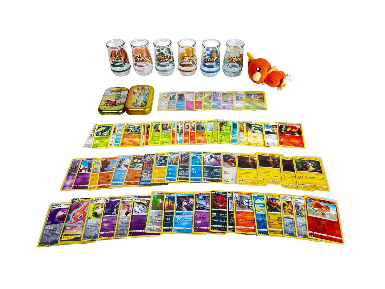 Pokemon Trading Card & Collectibles Lot: Mixed lot of Pokemon trading cards and collectibles, featuring a wide assortment of standard, holo, and reverse holo cards spanning multiple series and generations. Also included are small Pokemon plu