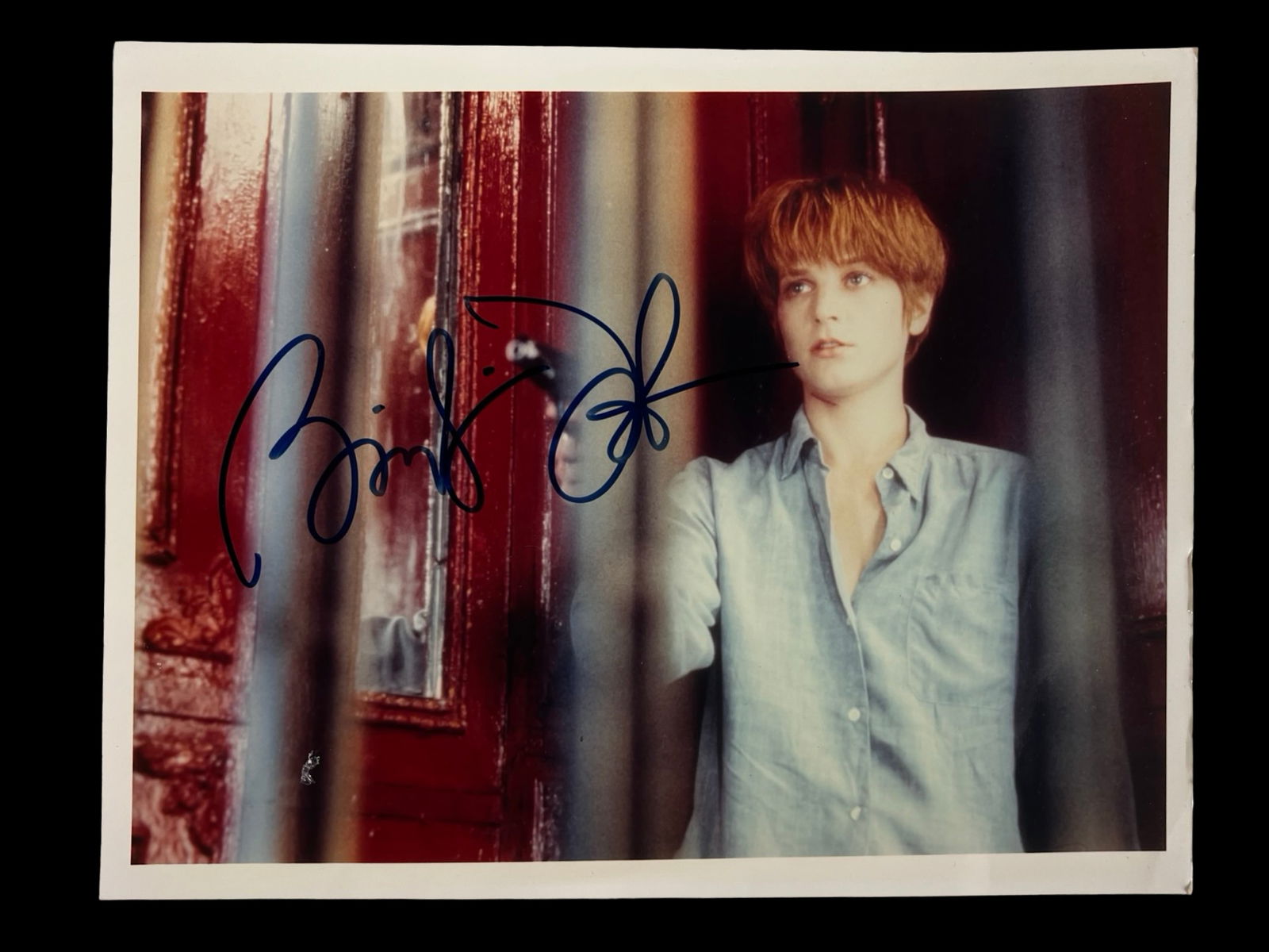 Bridget Fonda Signed Autographed Photograph: Color portrait of actress Bridget Fonda, boldly signed across the image in blue ink. A striking autographed photograph capturing the Hollywood star known for her memorable roles in 1990s cinema.An