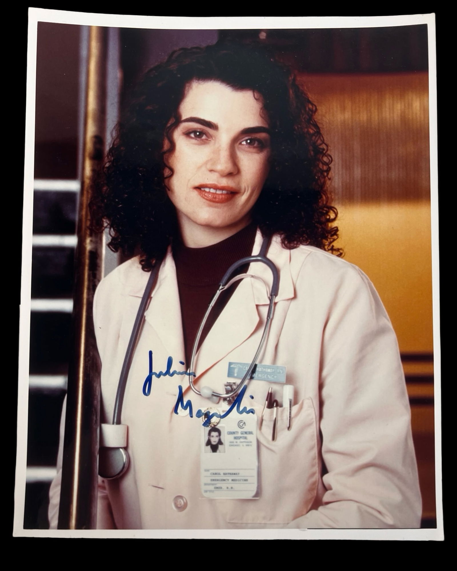 Julianna Margulies Signed "ER" Photograph: Photograph of Julianna Margulies in her iconic role as Nurse Carol Hathaway from the hit television drama ER. The image captures her in hospital attire with stethoscope, representing one of the most b