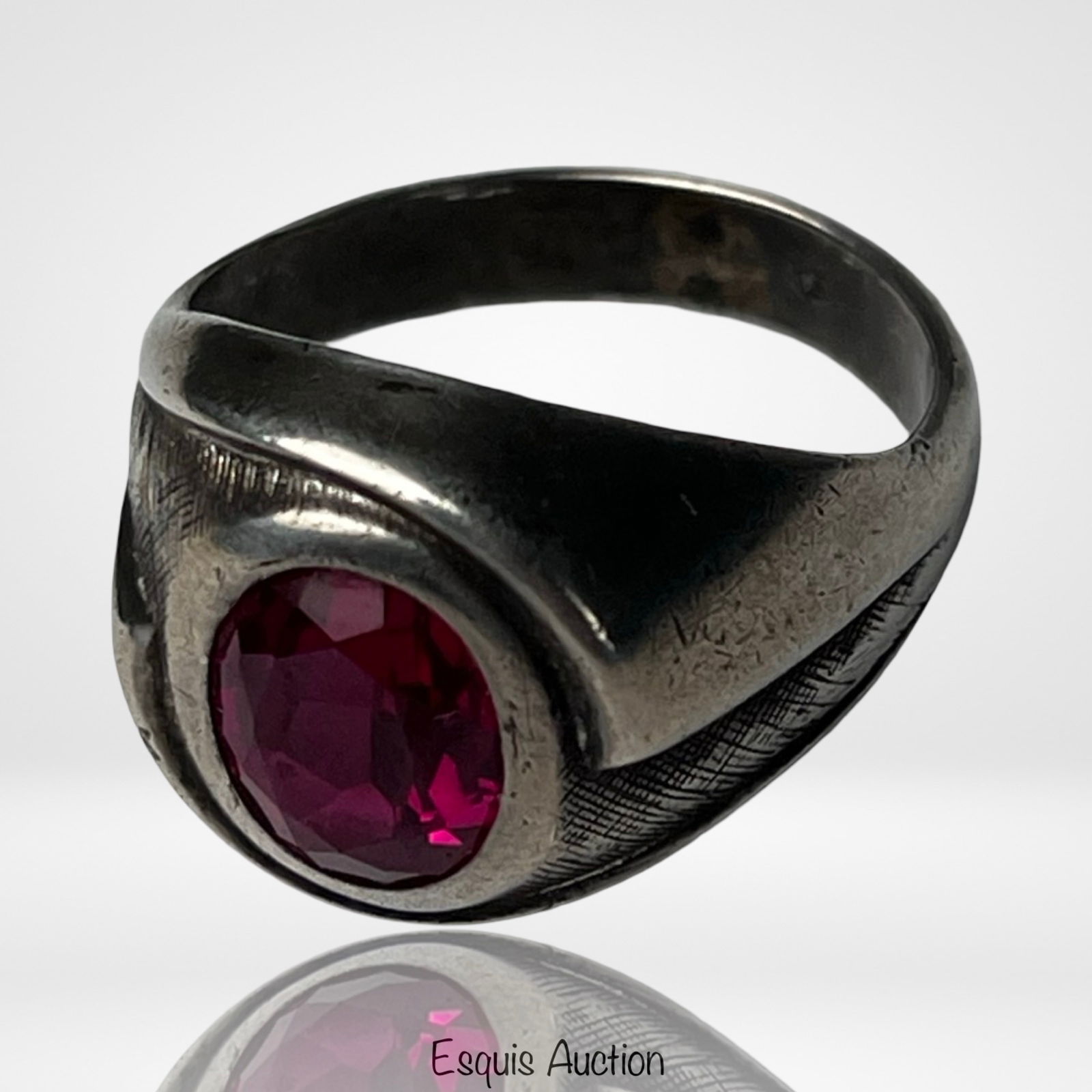 Sterling Silver Ring with Faceted Red Stone: Bold sterling silver ring featuring a bezel-set faceted red stone, likely glass or synthetic ruby, mounted in a substantial modernist-style setting. The ring displays a wide tapering band with engrave
