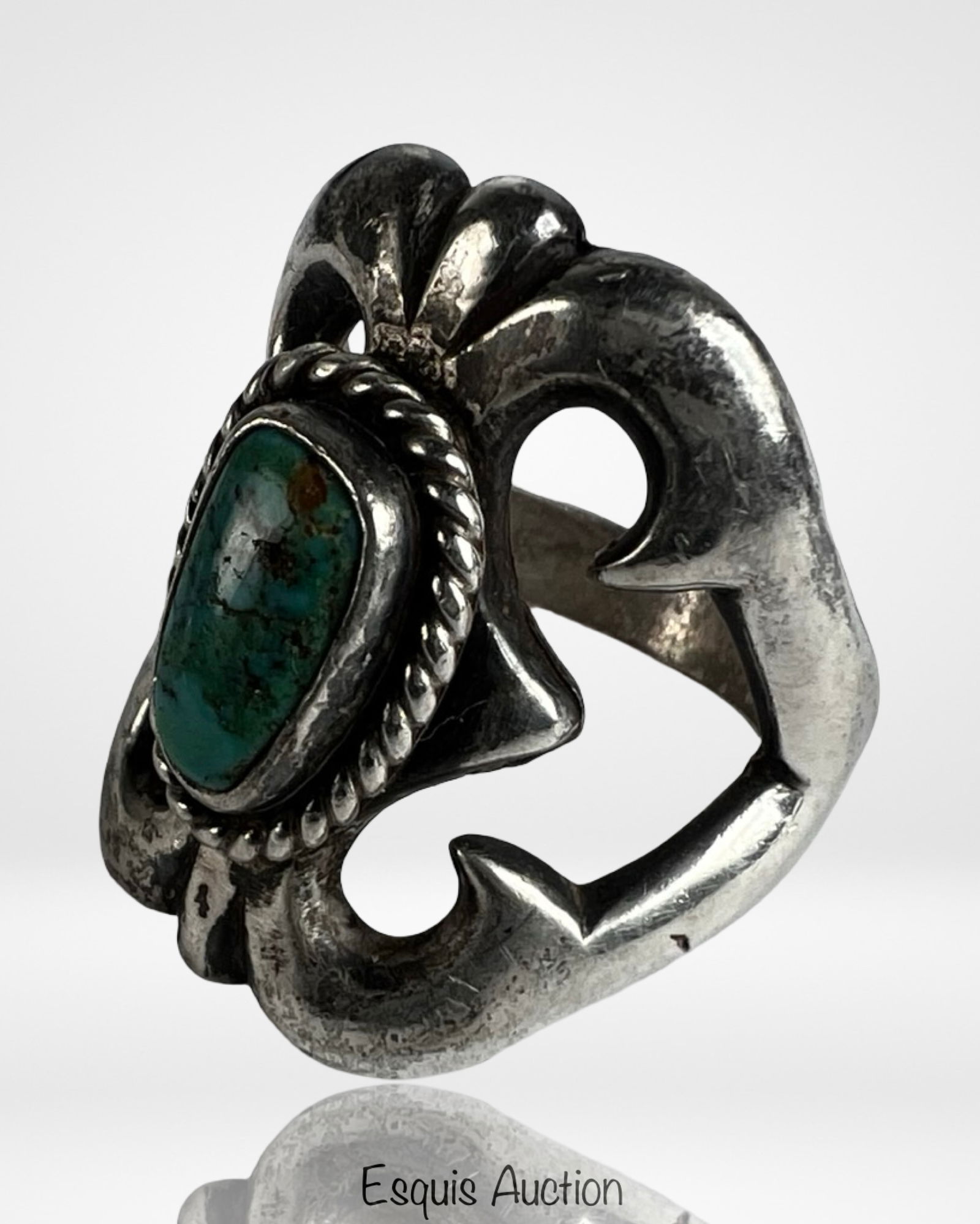 Navajo Sandcast Sterling Silver Turquoise Ring: Striking Navajo sandcast sterling silver ring featuring a natural turquoise stone set in a raised bezel with twisted rope border. The design showcases a bold, sculptural form with flowing, organic