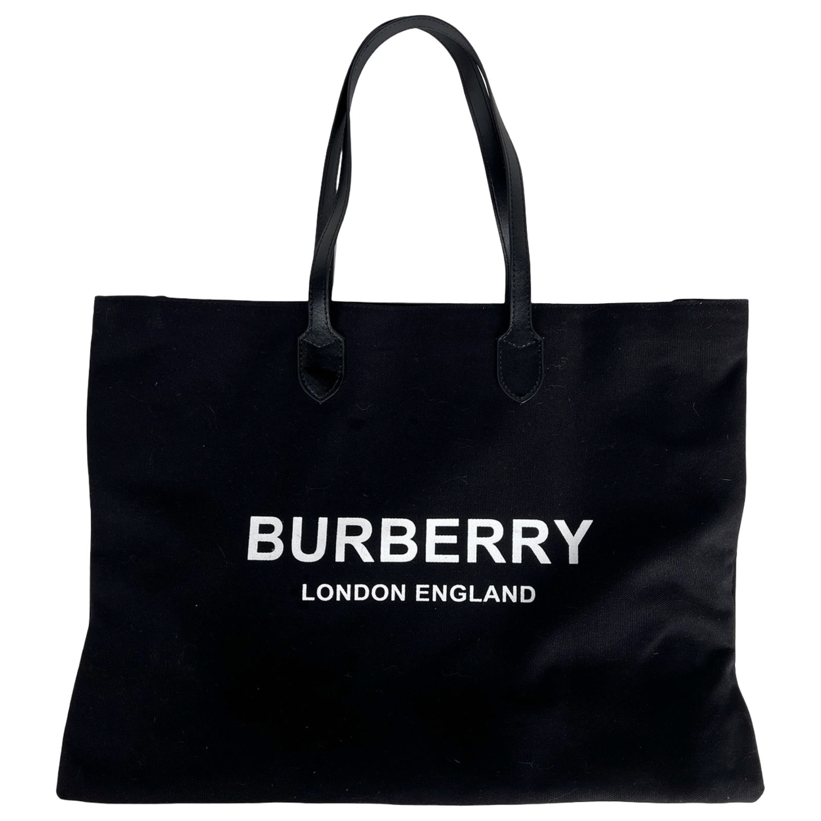 Black Canvas Tote Bag with Leather Handles: Sleek black canvas tote bag featuring sturdy double leather shoulder straps and a spacious open interior. The front displays bold white lettering, while the interior includes a zippered pocket for