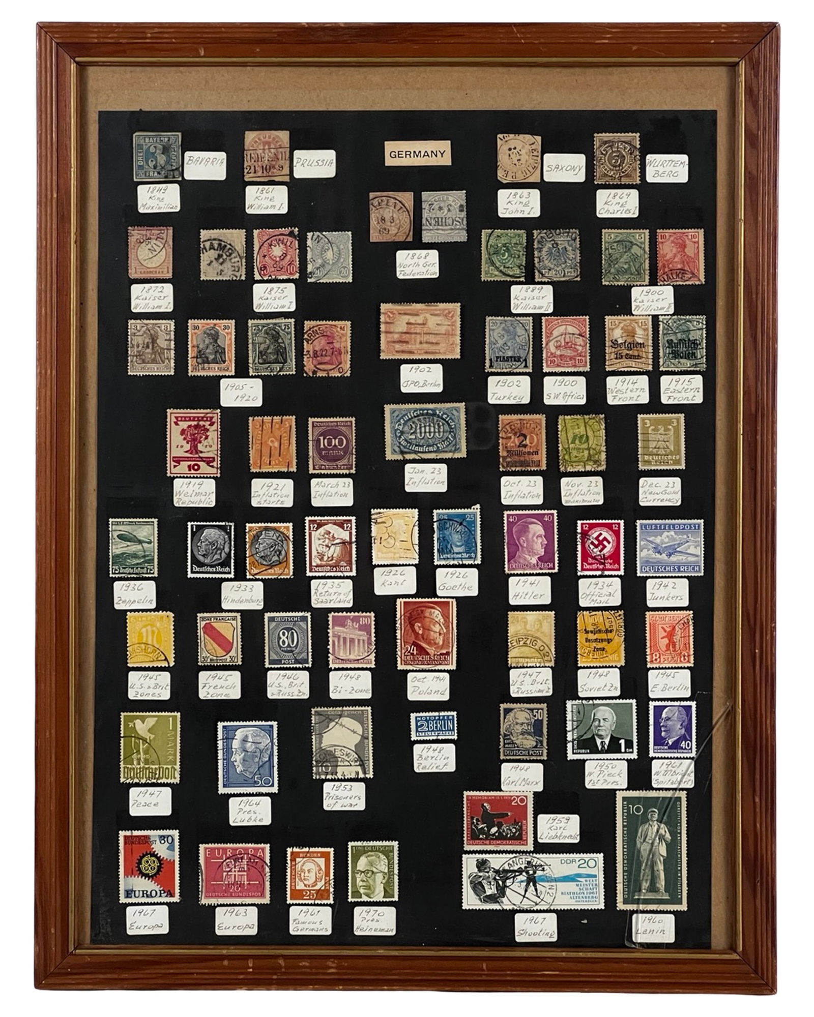Framed German Stamp Display Bavaria Prussia Reich: Framed display of German postage stamps spanning the mid-19th century through the post-war period, attractively mounted and labeled on a black backing. The collection includes early states such as Bav