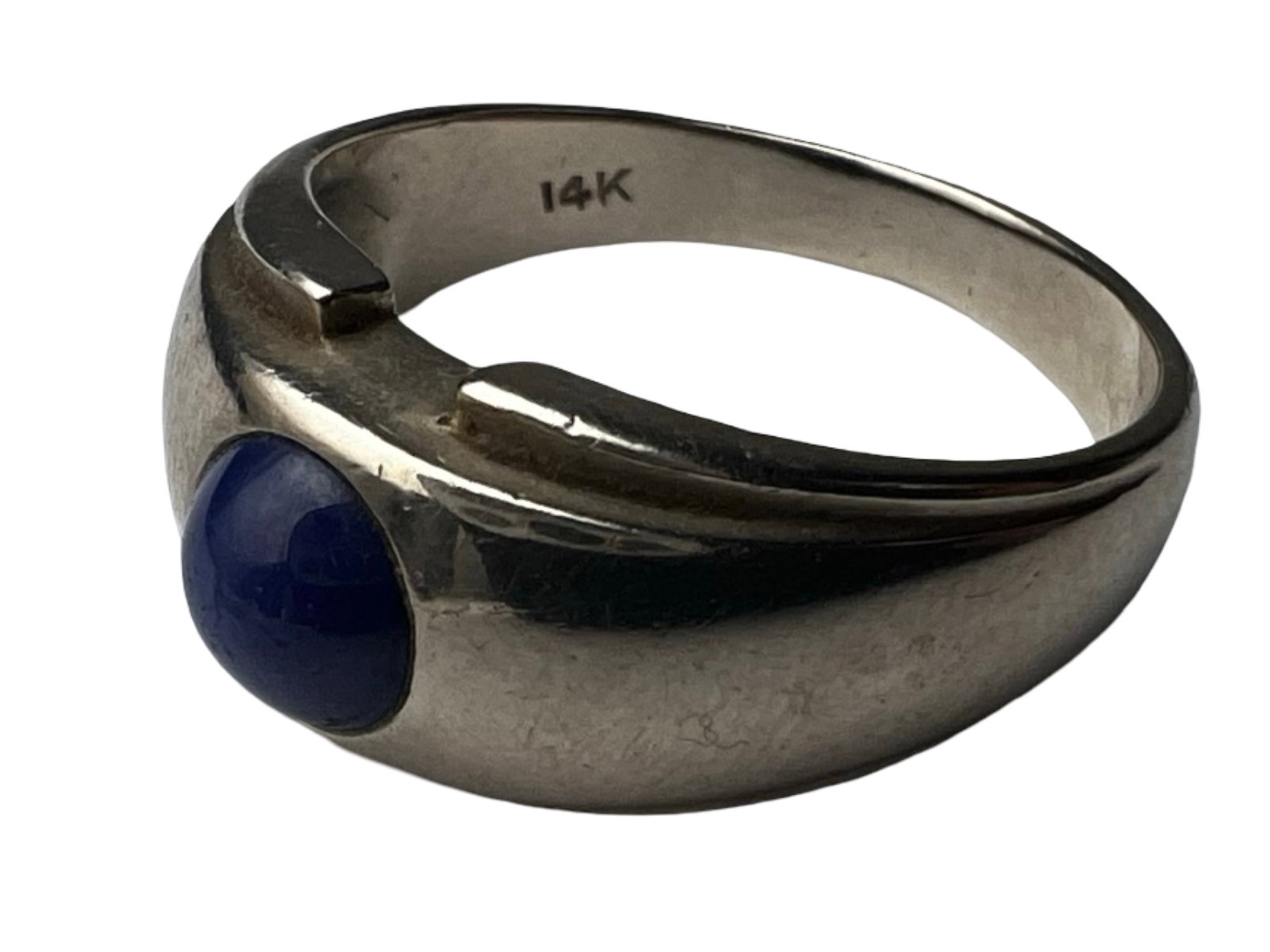 14K White Gold Ring Blue Star Sapphire Cabochon: Elegant 14K white gold ring set with a polished blue cabochon stone exhibiting star sapphire characteristics. The stone displays a rich deep blue tone with a smooth domed surface, set within a sleek, 