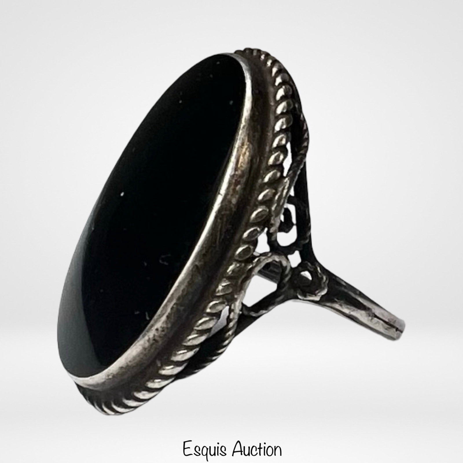 Sterling Silver Black Onyx Statement Ring: Description:Sterling silver lady's ring featuring a large oval cabochon black onyx stone set in an elegant openwork mount. The setting is accented with twisted rope detailing and decorative scrollwork