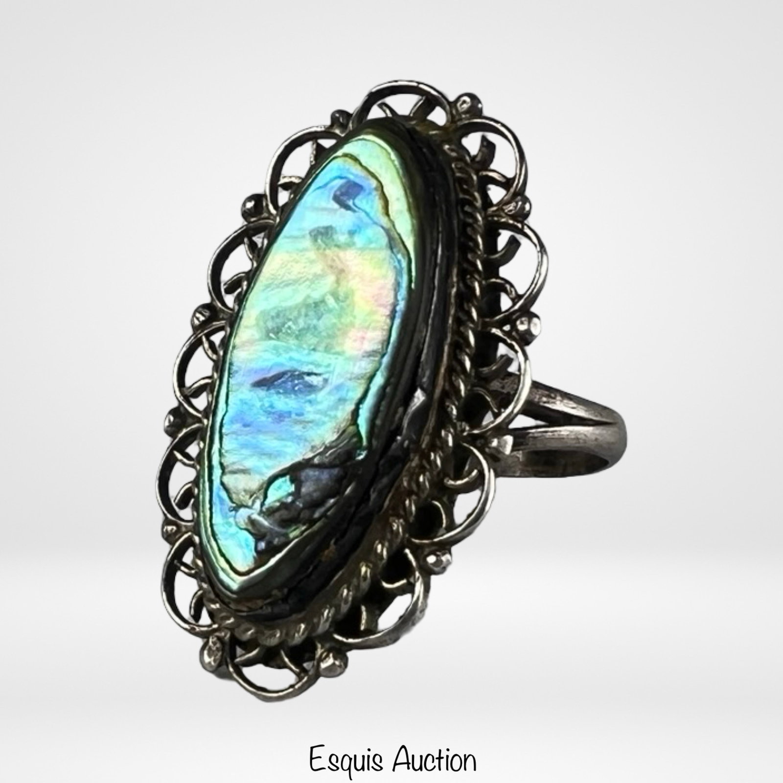Taxco Sterling Silver Abalone Shell Filigree Ring: Elegant vintage Taxco sterling silver ring featuring a luminous abalone shell cabochon displaying vibrant iridescent tones of blue, green, and pink. The elongated setting is framed by an ornate openwo
