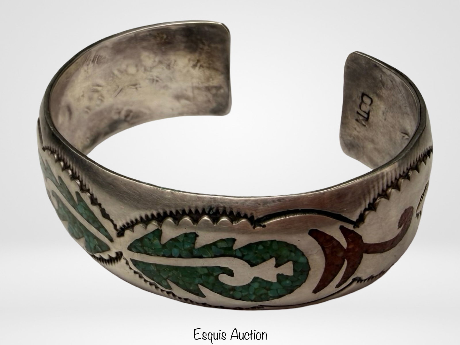 Navajo Delvin J Nelson Sterling Silver Bracelet: Striking Navajo sterling silver cuff bracelet by Delvin J. Nelson, featuring intricate inlay work with crushed turquoise and coral set within a bold, traditional design. The front displays a symmetric