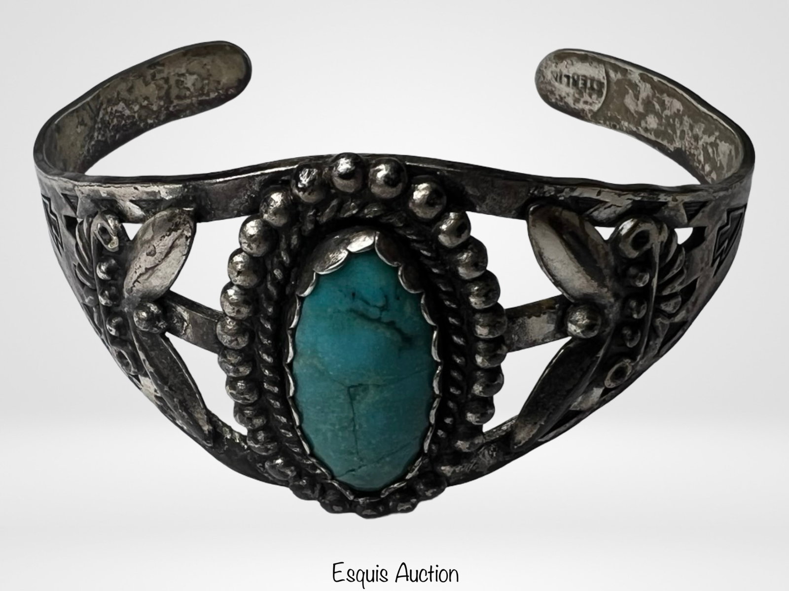 Navajo Sterling Silver Turquoise Cuff Bracelet: Striking Navajo sterling silver cuff bracelet featuring a large oval turquoise stone set in a traditional sawtooth bezel and surrounded by detailed silver beadwork. The cuff is further adorned with ha