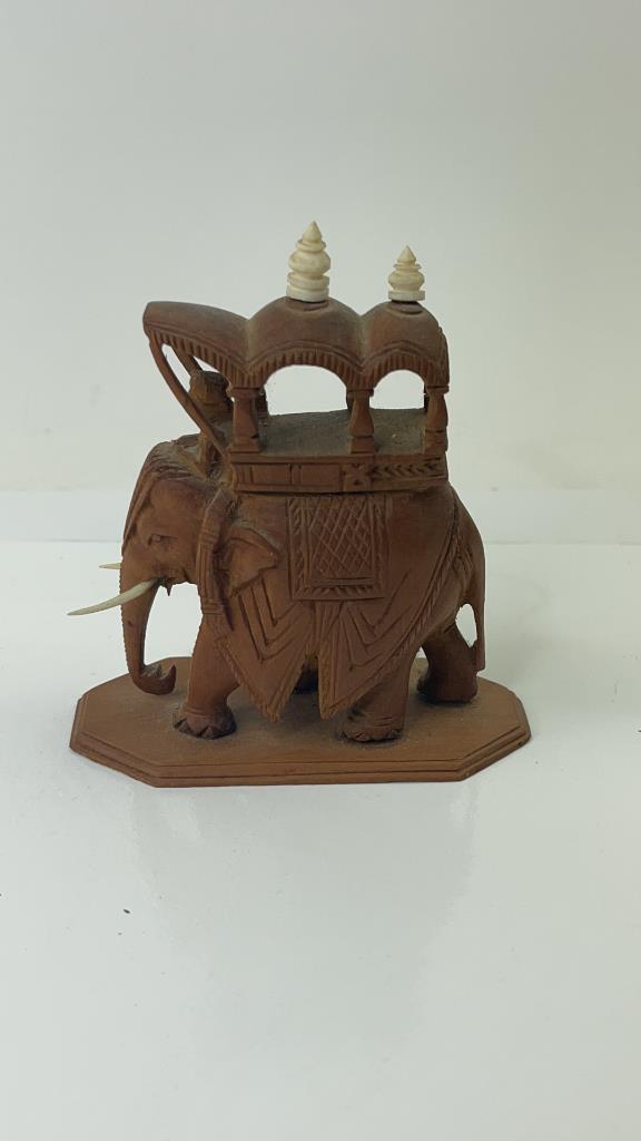Small Indian carved Wood Elephant Sclupture: Very cute little elephant with hut on top. Complete with tusks and little toppers. Good Overall condition. Measures about 3.5"L x 3 3/4"T