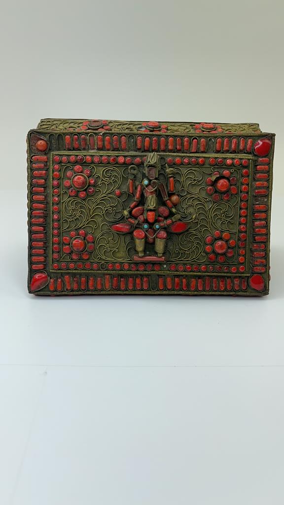 Antique Brass Tibetan Box with Blue and Red Stone: Antique very detailed brass tebitan trinket box with natural red and blune stones. Has a statue figure on the front Good overall condition. Some stones missing and dings from age and wear. Measures ab