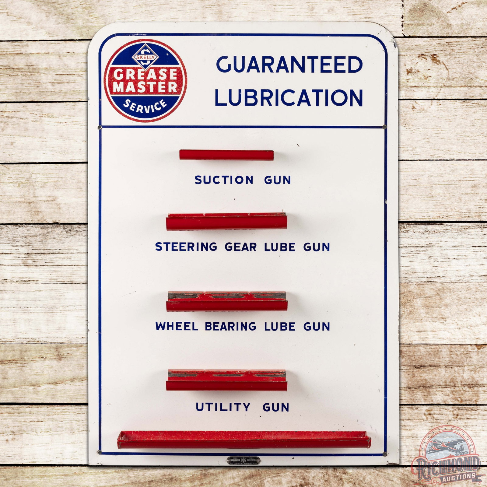 Skelly Grease Master Service Guaranteed Lubrication Service Station Grease Gun Display Sign w/ Logo: SST (single sided tin) grease gun board sign with cookie cutter edge has good color and shine. The field exhibits fine scratches with small paint chips and areas of paint loss to the grease gun holder