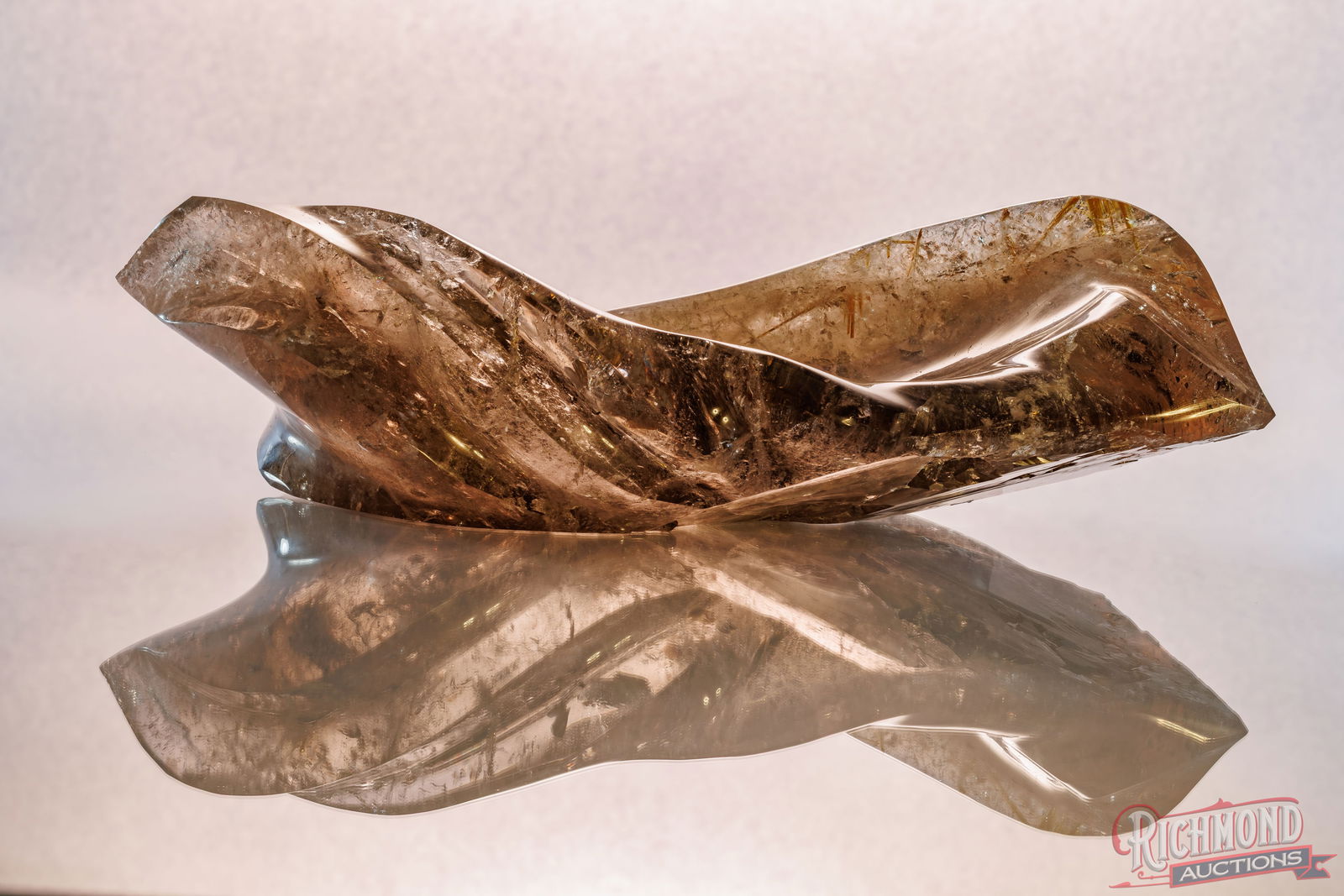 Smokey Quartz Sculptural with Massive Golden Rutile Inclusions: This elongated smoky quartz has been carved into a sculptural vessel form, emphasizing flowing lines and an elegant, leaf-like silhouette. Throughout the piece, abundant golden rutile inclusions creat