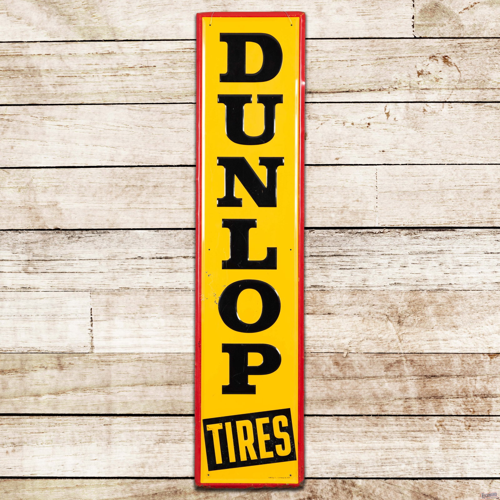 1957 Dunlop Tires Emb. Single Sided Tin Sign: SST (single sided tin) embossed self-framed sign has excellent color and shine. The display has light wear in the field with small scratches and paint chips in the left and lower outer field. The peri