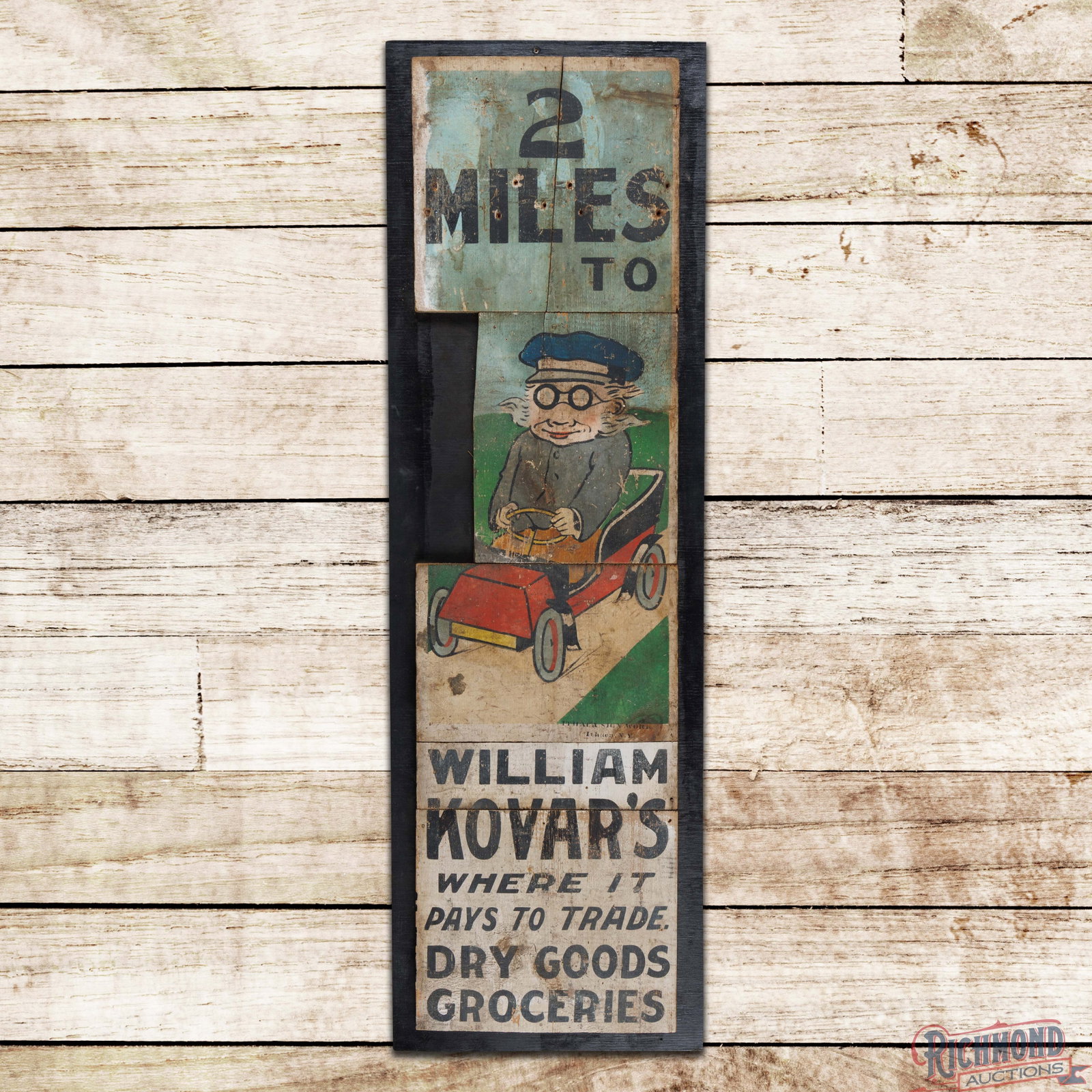 2 Miles to Williams Kovar's "Where it Pays to Trade" Wooden Ithaca Sign w/ Driver & Auto: Single sided wooden sign has good color and shine. The sign has been cut into five smaller pieces and attached to a larger black wooden board. The display has discoloration, surface wear, non-factory 