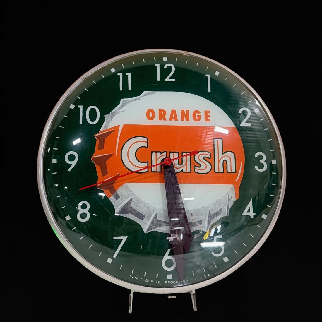 Orange Crush Pam Light Up Clock: Clock works but light does not. 15" H x 4" W. All items are eligible for free delivery to Rustbelt Americana in East Moline, IL on 8/6-7 or other shows that Richmond Auctions attends. Size 15" H x 4"