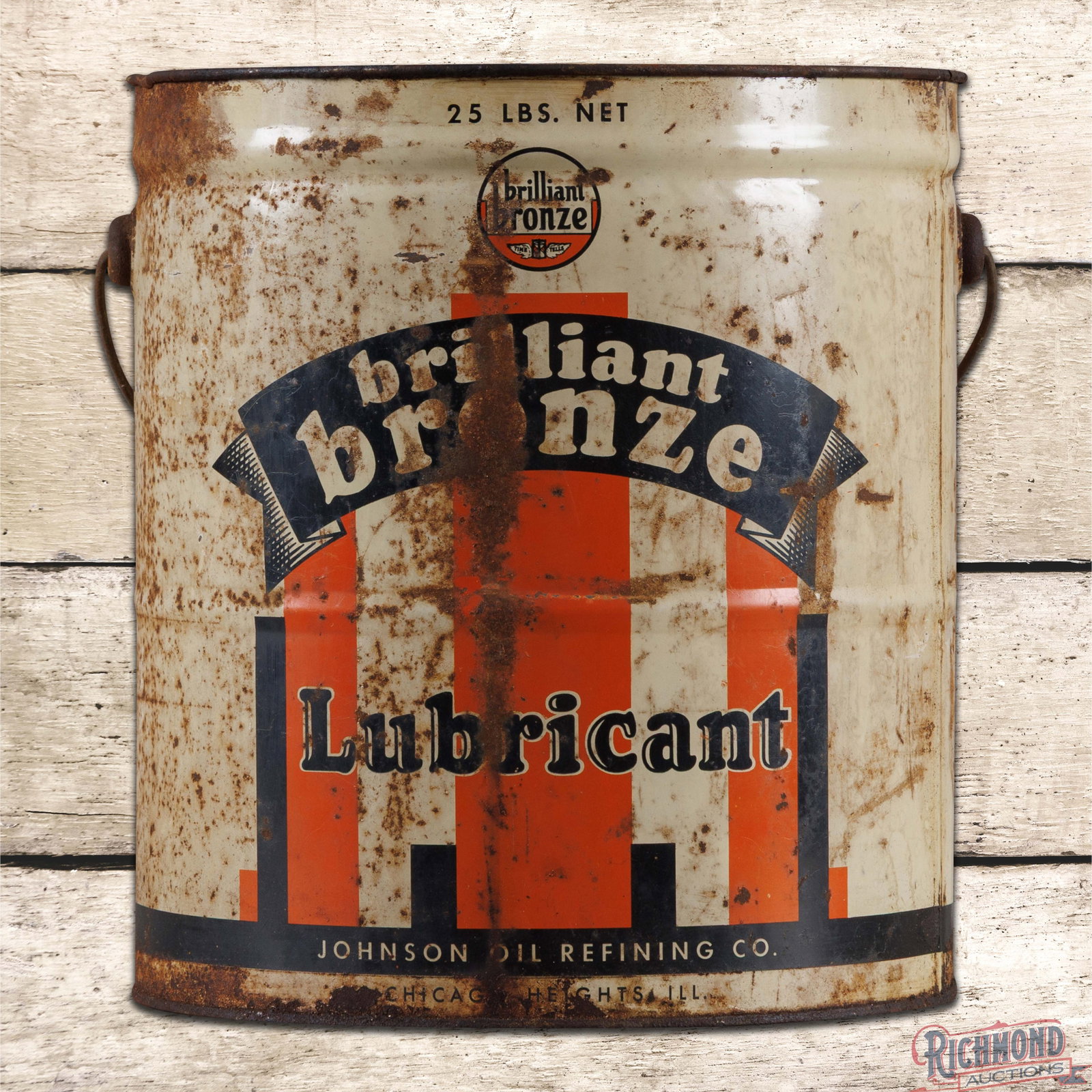 Johnson Brilliant Bronze Lubricant Empty 25 Pound Metal Grease Can: Empty 25-pound metal can has good color with moderate shine. The handle is present and the lid is missing. The can has general wear throughout with oxidation and paint loss. The reverse has heavier we