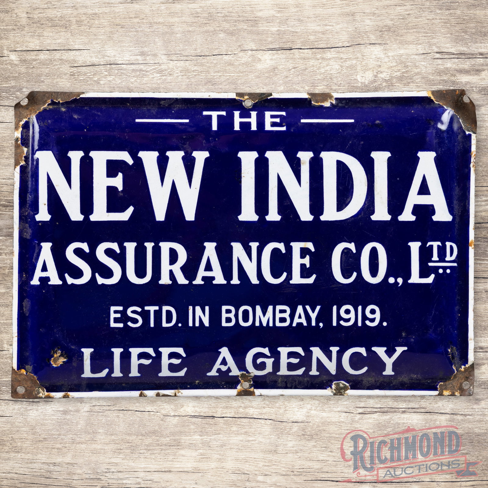 The New Indian Assurance Co. Ltd Life Agency Convex Single Sided Porcelain Sign: SSP (single sided porcelain) pillow sign has very good color and gloss. The display has surface wear with areas of minor discoloration. The perimeter has chips with bends at the corners. The sign has 