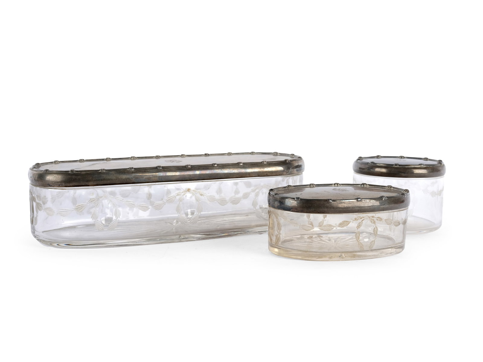 TOILETRY SET: 3 LIDDED JARS, CIRCA 1900: Toiletry set: 3 lidded jarsCirca 1900Rectangular jar, oval jar and round jarMonogrammedClear glass with silver lidsHallmarked silver (Diana head)Length 23 cm and 11 cm; diameter 8 cmTotal weight of