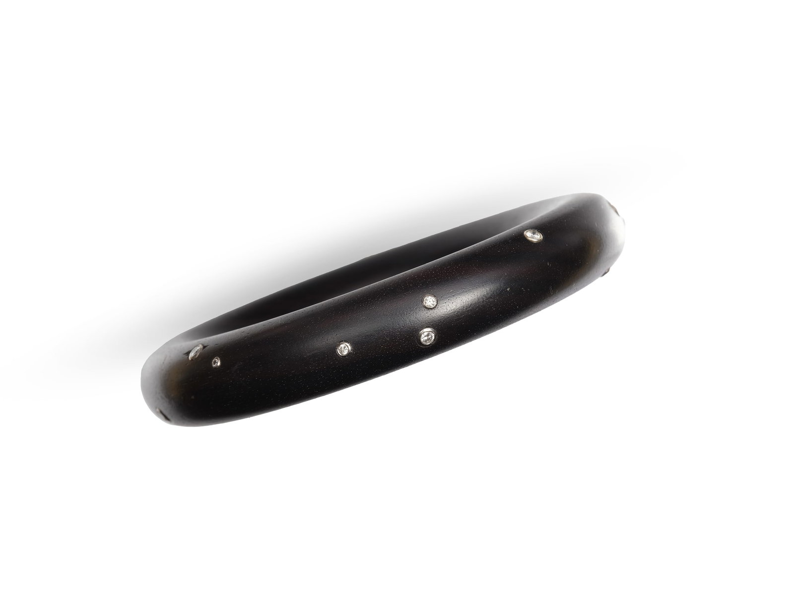 WOODEN BANGLE, ADORNED WITH 14 DIAMONDS AND ONE RUBY, TOTAL APPROX. 0.75 CT: Wooden bangleAdorned with 14 diamonds and one ruby, total approx. 0.75 ctDiamonds set in 18-karat white goldInner diameter 6.5 cm, outer diameter 9.7 cmWeight 65.8 g