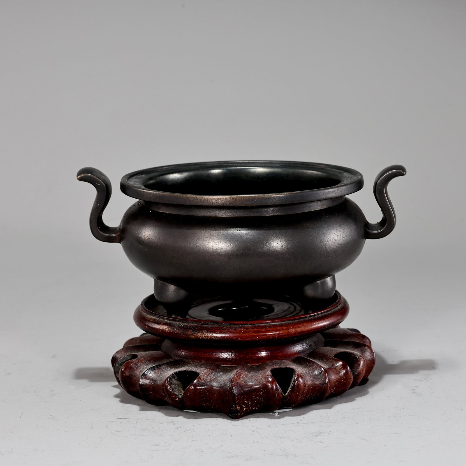 Chinese Bronze Censer with Carved Hardwood Stand: Chinese Bronze Censer with Carved Hardwood Stand (16 x 12 x 6 cm) Description: The censer features a rich dark brown to black patina with a smooth, understated finish, suitable for use as an incense b