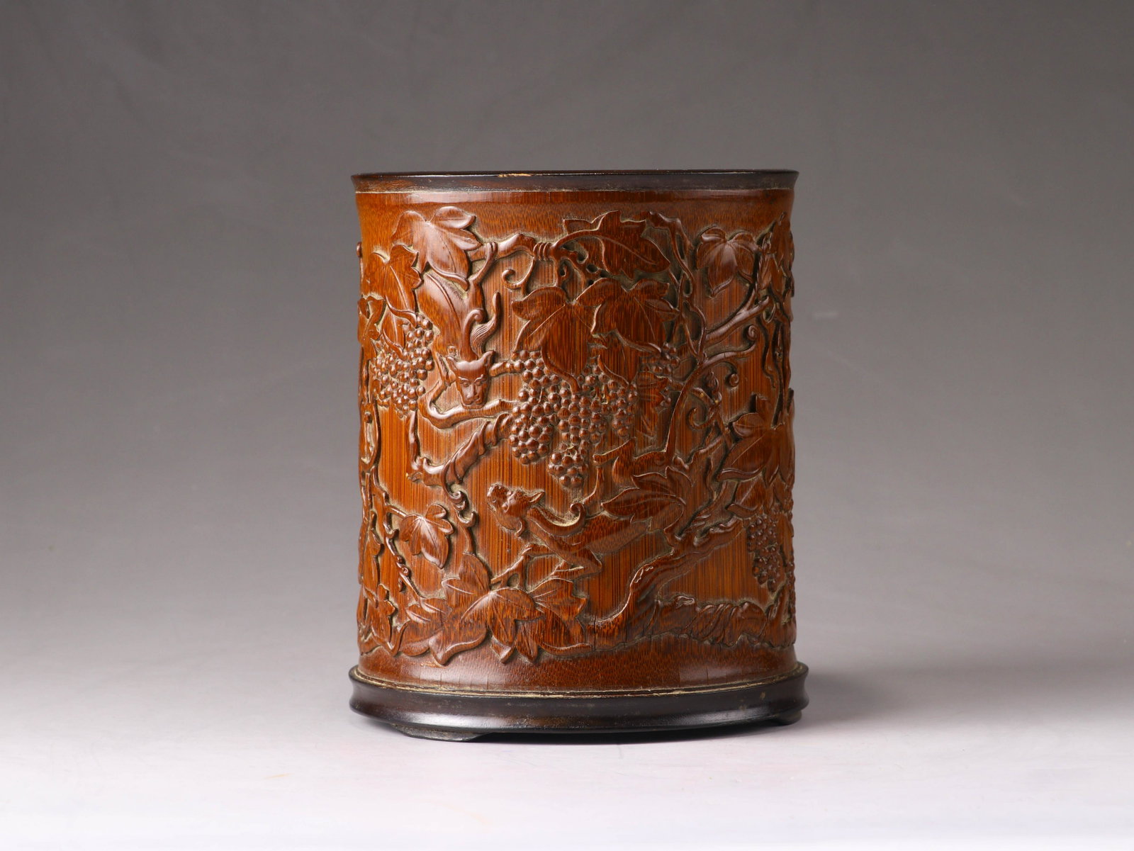 A Chinee bamboo brush pot: A Chinee bamboo brush pot, high-relief carved with lions amongst grape vindes, H 15 - Dia 12 cm