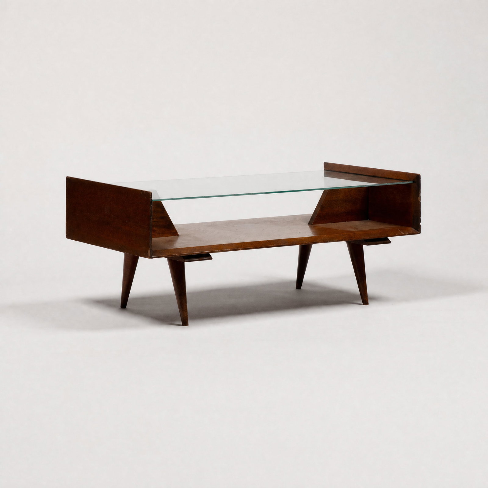 In The Manner of Gio Ponti, Cocktail Table: Italy, c. 1950 17 1/8" x 41 1/2" x 21" glass, walnut veneer, brass screws Having slotted glass surface with geometric supports. This item is located in our Treadwell, NY warehouse. Pickup and