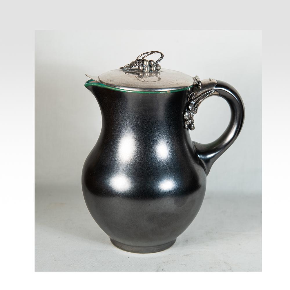 Michael Andersen ceramic pitcher Schleissner silver: Stunning piece, breathtaking gun metal glaze with slight iridescence. Silver is beautifully wrought in a danish style with a light hand hammering. Marked with incised Andersen mark and 9361 on bottom.