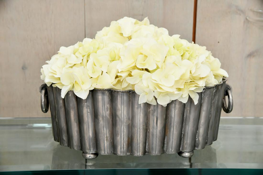 Faux Hydrangea Display In Ribbed Oblong Planter: Add a touch of nature to your decor with this Faux Hydrangea Display In Ribbed Oblong Planter. Made with a durable metal this planter features realistic looking hydrangea flowers arranged in a row tha