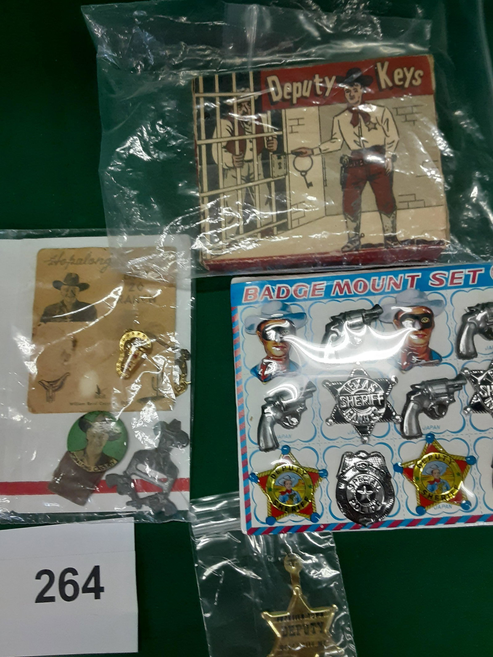 Selection of law enforcement toys including Hopalong Ca: Deputy Keys with 3 keys in original box. Hop-along Cassidy Pin and Giveaway pin with a pistol that goes in the hostel. Frontier Town 1964-1968. Sheriff badge. Never been used. Lone Ranger style. Shipp