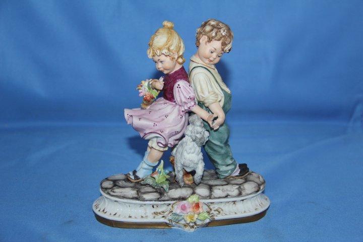 Capodimonte Porcelain Statue of Two Children: 13-4283 Capodimonte porcelain statue of two children and a dog. Artist signed, Vier Tasca. 7 in. tall. Base is 5 1/2 in wide.