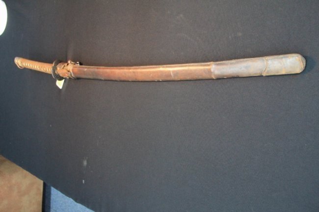 Sword - Japanese Army Officer Shin Gunto: 115-6219 Sword. 39 in. long. Weapon is in very good condition, with ancestral signed blade rather than standard fittings. Hilt bale and sword know are missing. Leather combat cover is present but show