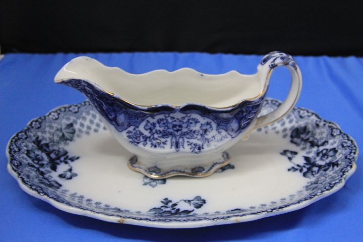 Flow Blue Gravy Boat and Platter: 125-6119 John Maddox & Sons Flow gravy boat and F & Sons Burslem flow blue platter. Gravy boat measures 8 in. long and platter measures 12 x 9 in.