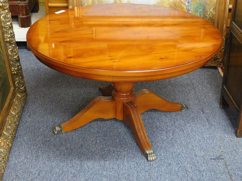 Round Yew Wood Coffee Table: Round yew wood coffee table with brass claw feet. Measures 21 inches tall and 38 inches diameter. Measures 21 inches tall and 38 inches diameter.
