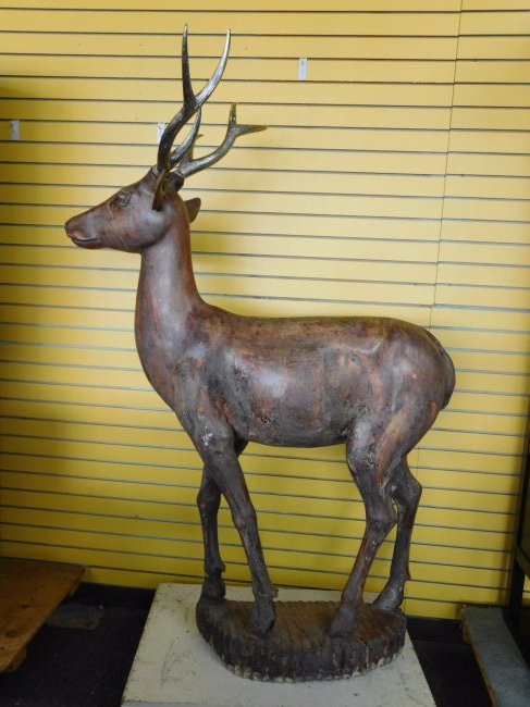 Wooden Reindeer Statue: Wooden reindeer statue on wood base. Silver gilt antlers. Measures 71 inches tall and 49 inches long.