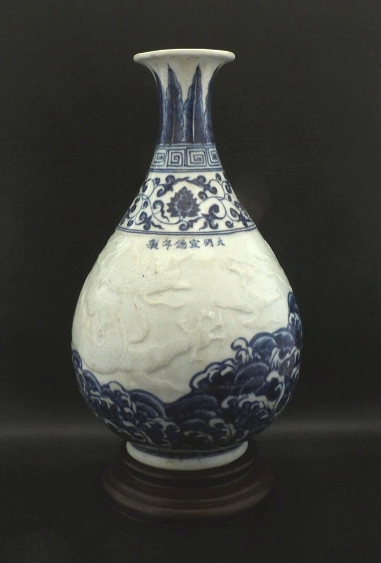 Chinese blue and White Dragon Vase: Chinese blue and white yuhuchun vase depicting with a raised dragon on the sea, six characters mark on neck with a carved stand. H 13 1/2” W 8" (vase)