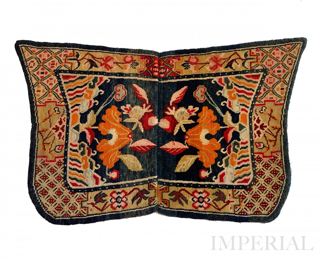 A FLORAL UNDER-SADDLE RUG, TIBET, 1920s: A Floral Under-Saddle rug, Tibet, 1920. Decorated on each sides with lilies sprouting from the water. Surrounded by floral and geometric design border. 95cm x 65cm.