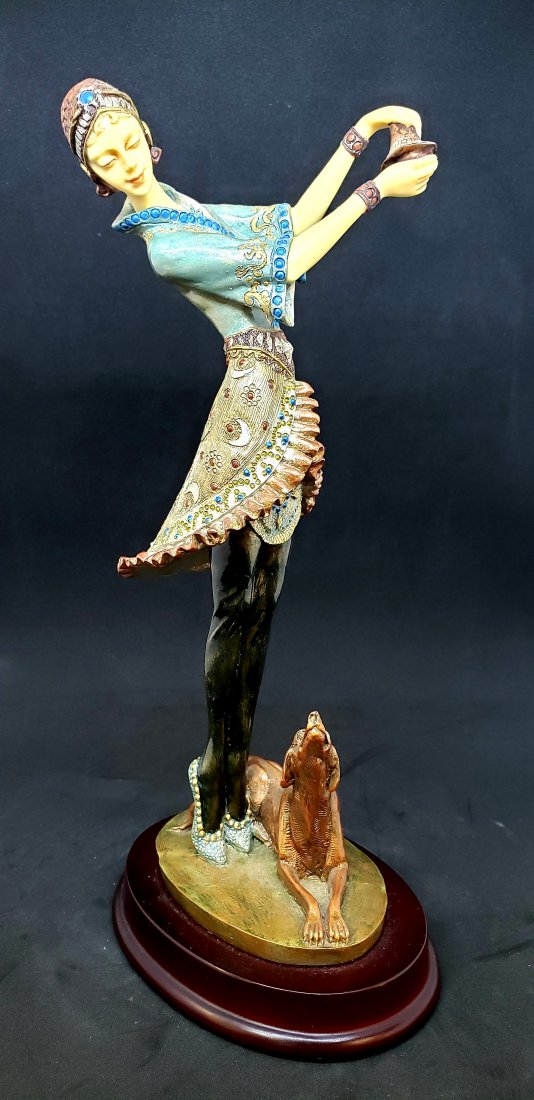 Vintage Art Deco Style Figurine of Woman with Dog: Exquisitely hand-crafted Art Deco style figurine of a woman with a dog by her side. The figure is mounted atop a wooden base. Made of resin. Dimensions: 11.25" H x 5.5" W x 4" D.
