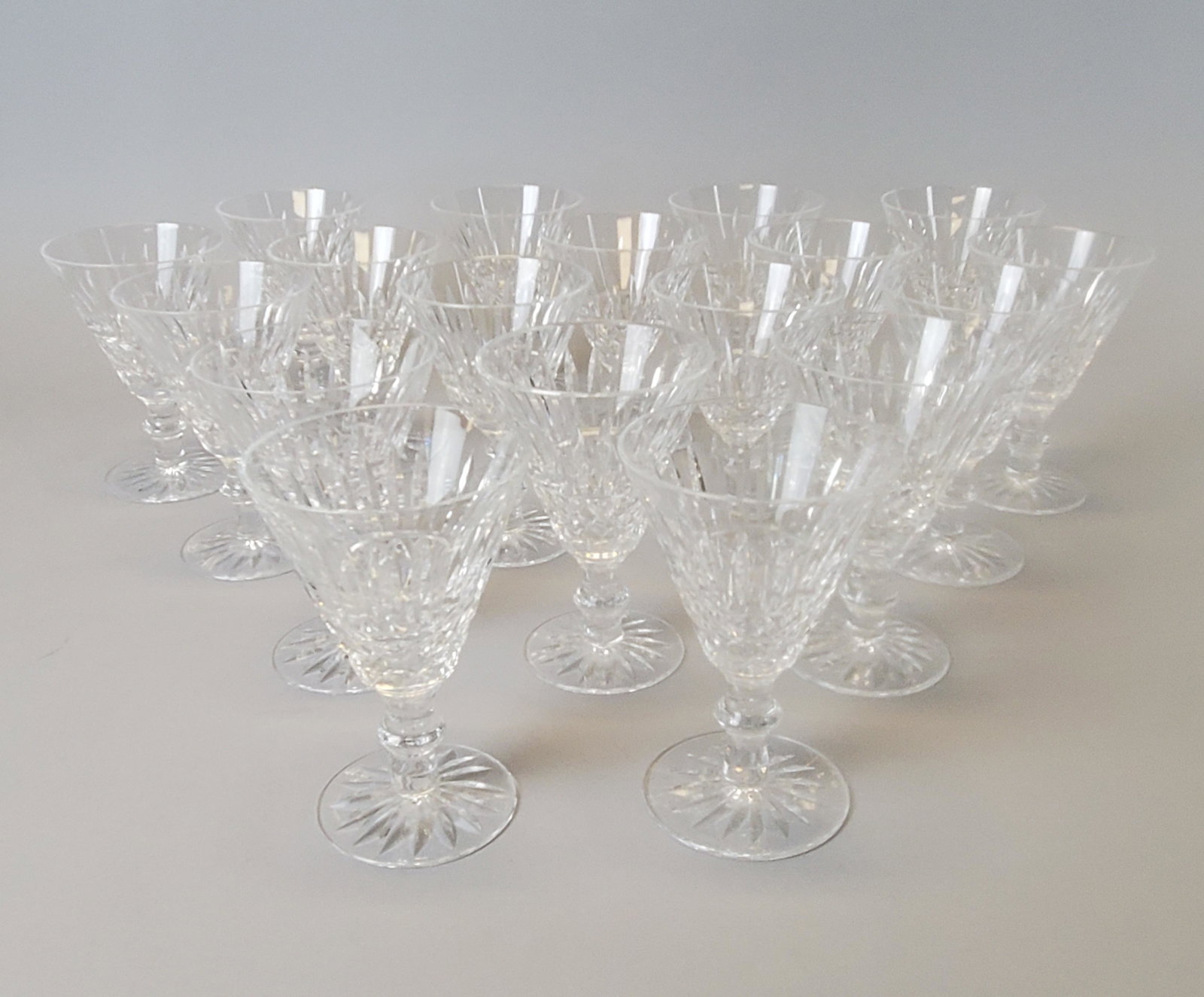 18 Waterford Tramore Pattern Crystal White Wine Glasses: Comprising 18 Tramore pattern white wine glasses, each with annular knop, the bases acid etched with company logo. 5 1/4"H. Condition: good, no damage or repair.