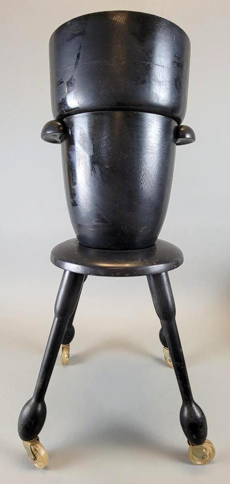 Mid Century Modern Wine Chiller on Stand: The black lacquered wood wine chiller surmounting a portable stool-style base with four protruding legs and castor wheels, central well to ice bucket with silvered mercury glass liner, ice bucket flan