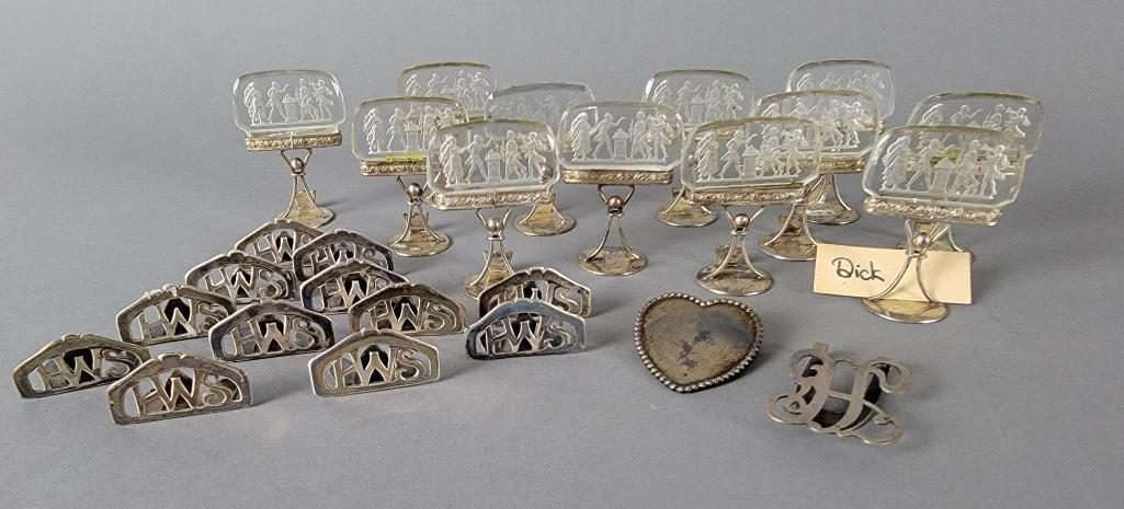 Lot of Silver Card Holders w/ Intaglios, inc. Sterling: Comprising twelve 2.5" silvered place card holders, each featuring a cut cameo glass intaglio medallion with an etched neoclassic scene, marked Austria, circa 1900. Also to include an antique hinged s