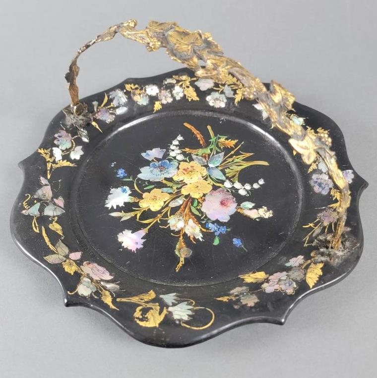 Mid 19th C Papier MachÃ© & MOP Cake Basket: The shallow circular black lacquered dish with lightly raised and scalloped edges, center and sides with decorative floral motifs; details with inlaid mother of pearl and gilt stencil work, has retrac
