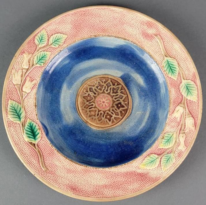 Antique 19th Century English Majolica Luncheon Plate: The rounded 9" form in muted pink with slightly raised and stippled edge featuring rose boughs, the central roundel with a decorative medallion suspended within a blue field; English, last quarter