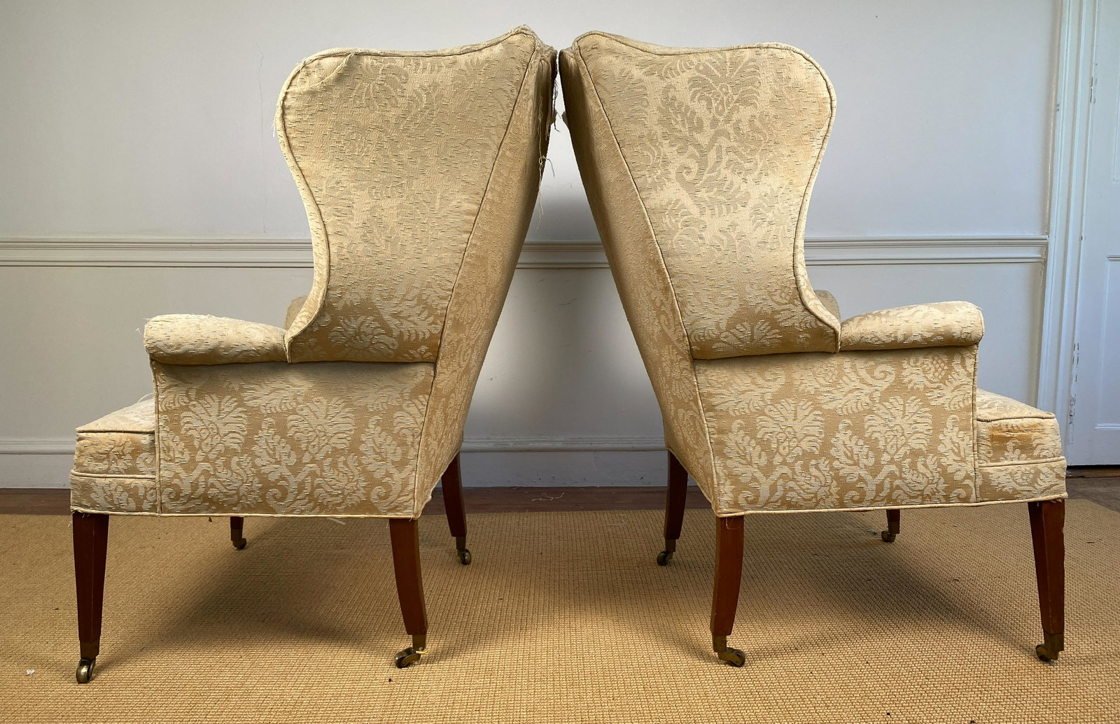 Pair Antique Chippendale Style Wing Back Chairs: Fantastic wing chair with rolled arm and unusual stretcher. Wood legs with caster rolling wheels. Fantastic shape, needs to be reupholstered. Seat height 18". Arm height 25".Fantastic wing chair with 