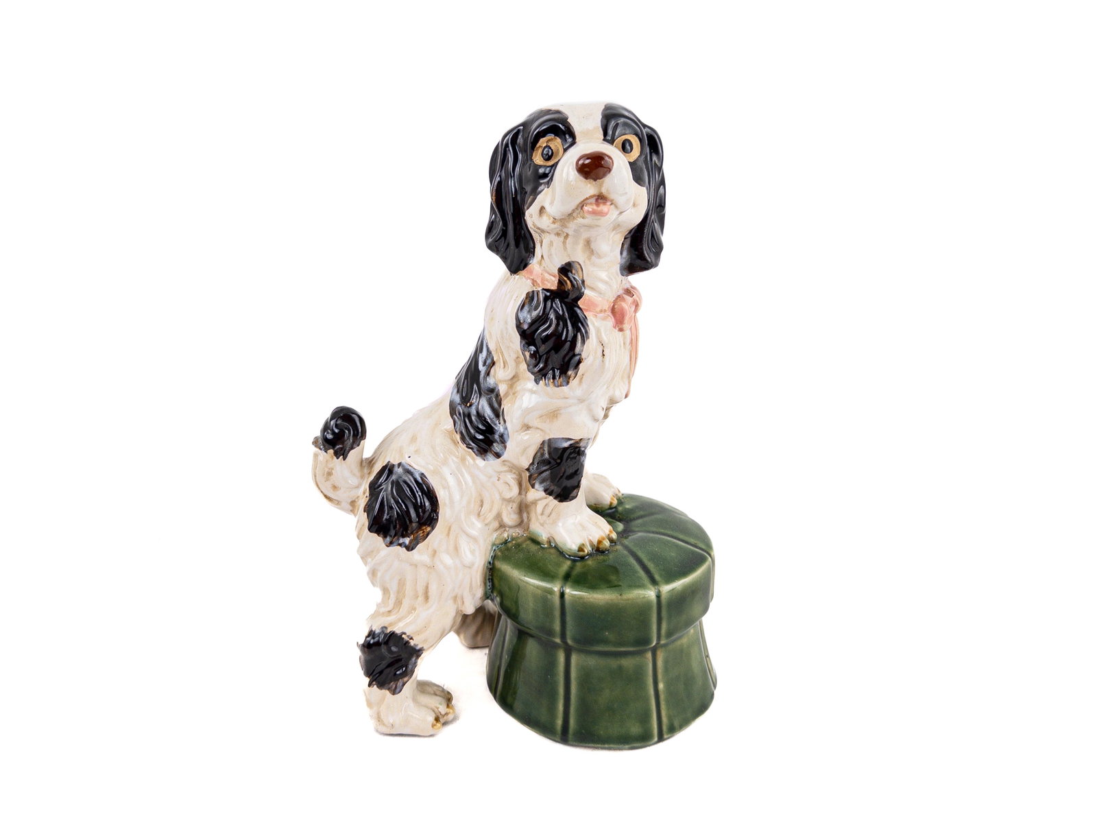 Staffordshire Disraeli Spaniel Figurine: Wide-eyed, hand-painted black and white Staffordshire spaniel perched on a green footstool. Dimensions Width: 8 1/4" Depth: 4 3/4" Height: 12 1/4"