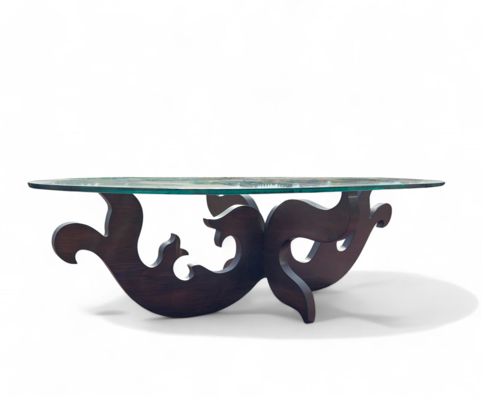 Eva Zeisel for Design Within Reach Coffee Table: Jigsaw style cut wood base with Eva Zeisel signature carries an oval glass top perfect for many living areas. Measures 58" W x 33" D x 18" H, Glass is 1/2 "Thick